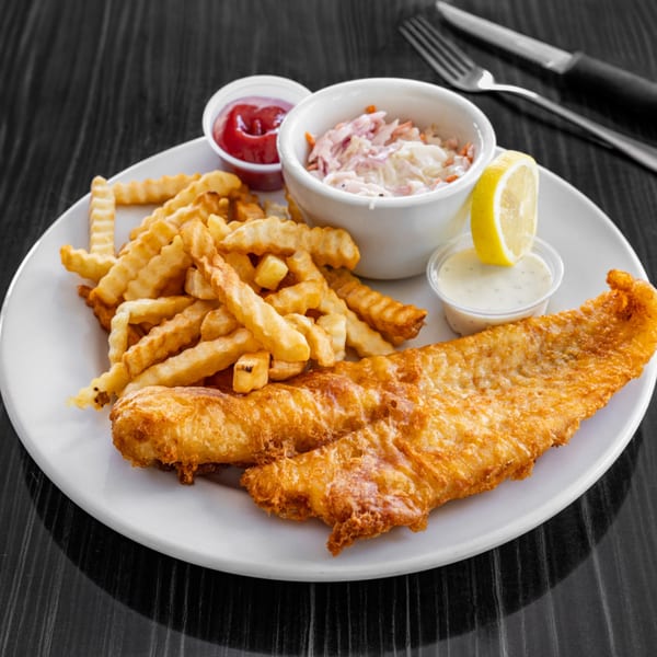 Victoria's Diner fish and chips with crinkle-cut fries, coleslaw, tartar sauce, ketchup, and lemon.