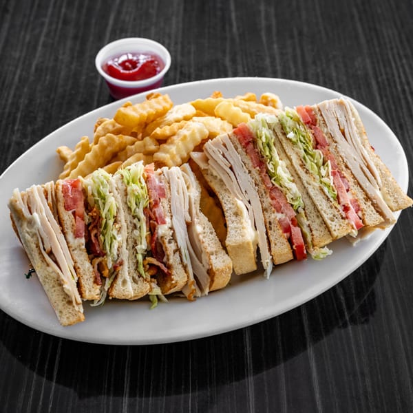 Victoria's Diner club sandwich with turkey, bacon, lettuce, tomato, and crinkle-cut fries with ketchup.